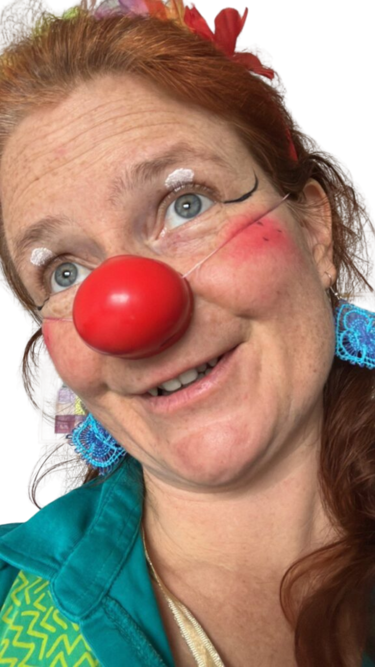 Marie-Gabriele Massa als fröhlicher Clown Tilotamma mit blauem Ohrschmuck, macht ein lustiges Gesicht