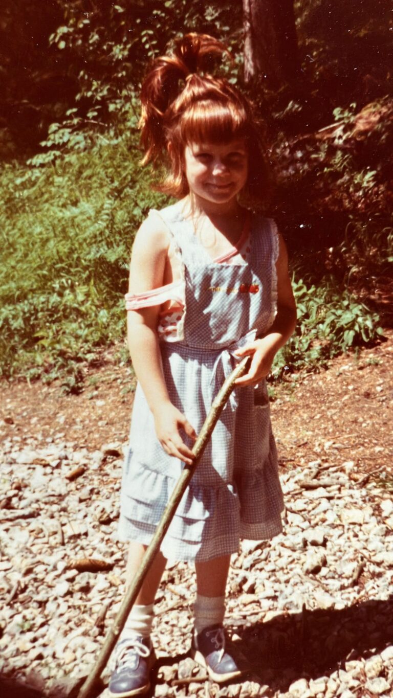 Marie-Gabriele Massa als Kind mit knorrigem Stock im Wald – glücklich und naturverbunden